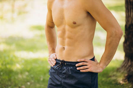 Cropped portrait of male sportive body isolated over outdoor background on bright summer dayの写真素材
