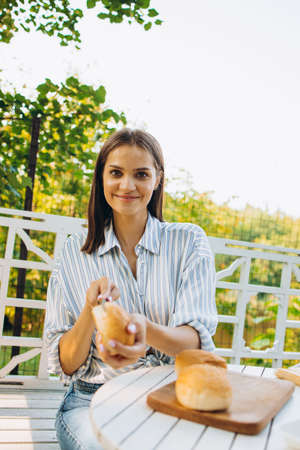 Portrait of young smiling girl preparing food and cutting burgers buns for picning eating on warm summer day outsideの写真素材