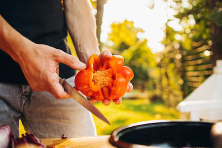 Friends cooking together in countryside for picninc gathering on warm summer day