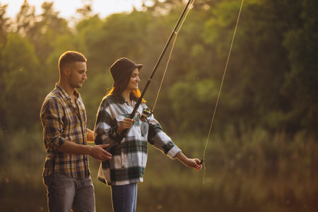 Portrait of young couple fishing on warm summer day in countryside at sunsetの写真素材