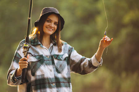 Cropped portrait of young beautiful girl fishing at sunset in coyntryside on warm summer dayの写真素材