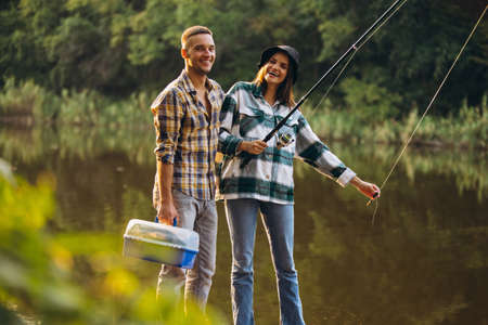 Portrait of young couple fishing on warm summer day in countryside at sunset