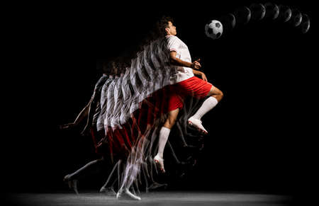 Portrait of young professional football player isolated on black background playing. Stroboscope effect.の写真素材