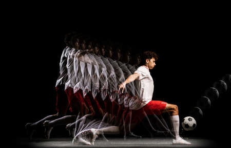 Portrait of young professional football player isolated on black background playing. Stroboscope effect.の写真素材