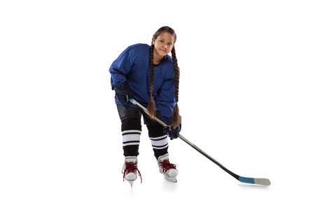 Full-length portrait of young female hockey player in blue uniform, with stick isolated over white white backgroundの写真素材