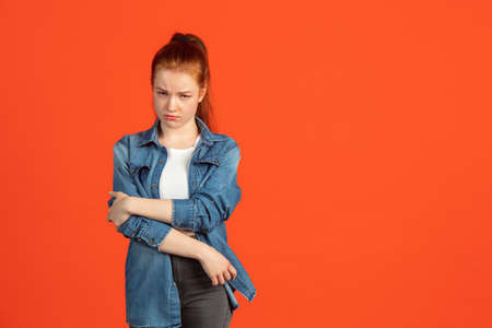 Resentful temper. Half-length portrait of young beautiful girl isolated over red backgroundの写真素材