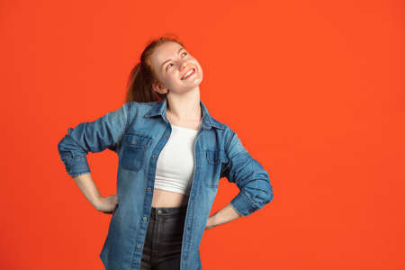Cropped portrait of one young caucasian woman smiling over red studio backgroundの写真素材
