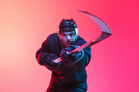 One man, professional hockey player training isolted over gradient pink background in neon