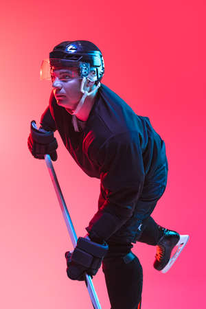 Side view portrait of professional hockey player training isolated over gradient background in neon lightの写真素材