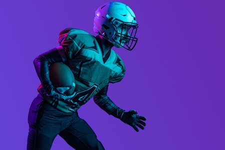 Cropped portrait of american football player in special uniform isolated over purple studio backgroundの写真素材
