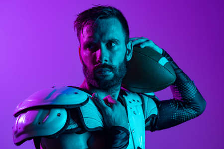 Cropped horizontal image of professional american football player looking away isolated over purple...