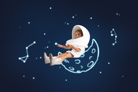 Creative artwork of little cute girl pretending to be astronaut isolated over dark blue background with white space drawings.の写真素材