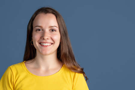 One caucasian girl smiling isolated over blue studio backgroundの写真素材