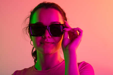 Close-up portrait of young caucasian girl in sunglases isolated over gradient studio background in...