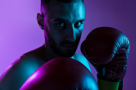 One professional male boxer training isolated over purple backgrund in neon light. Punchingの写真素材