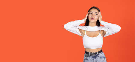 One beautiful caucasian girl in fashionable clothes posing isolated over orange background. Air kiss. Flyerの写真素材