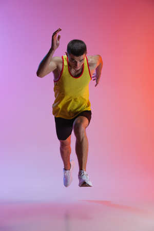 Portrait of young male athlete running isolated over gradient studio background. In motion