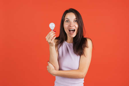 One beautiful caucasian girl posing isolated over red background. Lightbulb - ideaの写真素材