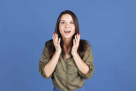 Cropped studio shot of excited young woman isolated over blue background