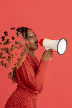 Creative collage of young african woman talking in megaphone. Female head consist of puzzle piecesの写真素材