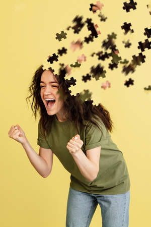 Modern collage of caucasian girl isolated over yellow background. Female head consist of puzzle...