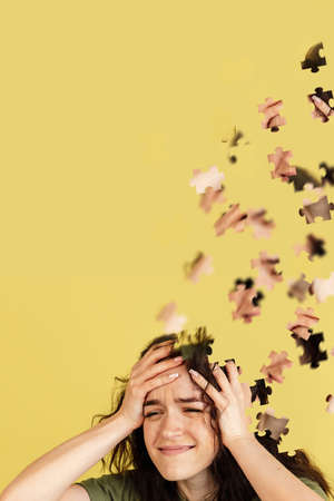 Creative collage of caucasian girl isolated over yellow background. Female head consist of puzzle pieces.の写真素材