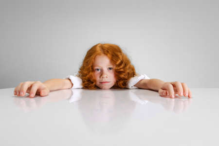 Portrait of little Caucasian cute girl posing isolated over gray studio background.