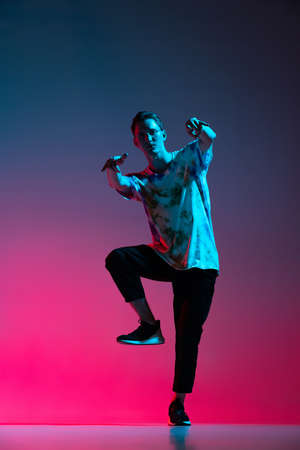 Vertical portrait of dynamic hip-hop dancer practising isolated over gradient pink purple background in neon lightの写真素材