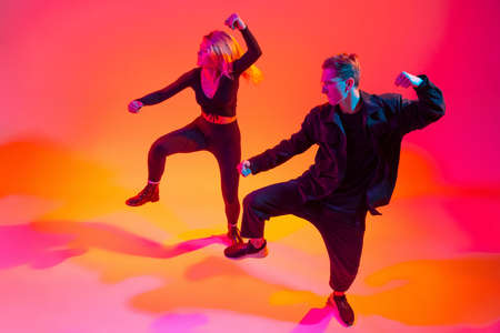 Expression. Two beautiful stylish hip-hop dancers on colorful gradient background in neon lightsの写真素材