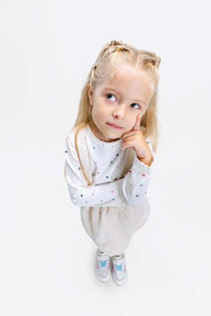 Top view portrait of little Caucasian girl, child posing isolated over white studio background....