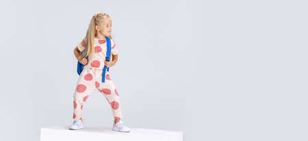 Full-length portrait of little Caucasian preschool girl with backpack posing isolated over white studio background. Flyerの写真素材