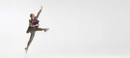 Full-length portrait of happy female employee in classical suit with folder jumping like ballerina...