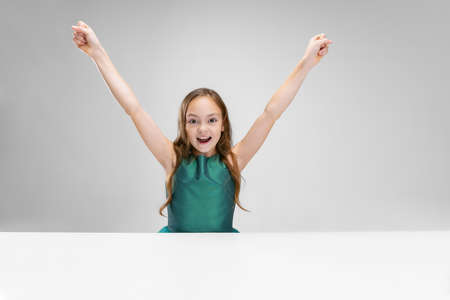 Cropped portrait of little girl, pupil feeling happy and excited isolated oer gray background