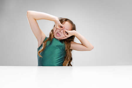 Portrait of little cute girl in posing with hands on eyes isolated over white studio background....