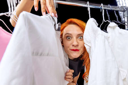 Cropped portrait of woman standing between clothes. Shop assistant, fashion expertの写真素材