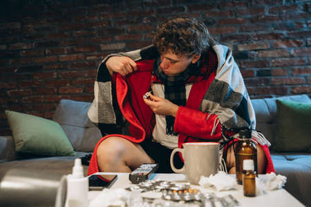 Cropped portrait of young man feeling bad, caught a cold, flu. Home self-isolationの写真素材