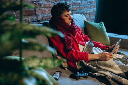 Portrait of young man feeling bad, having cold and flu, resting at home. Self-isolationの写真素材