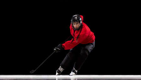 Full-length portrait of professional female hockey player training isolated over black background. Stickhandlingの写真素材