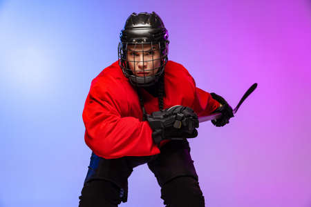 Cropped portrait of professional female hockey player, goalkeeper training isolated over gradient blue purple background. Concentrated playerの写真素材