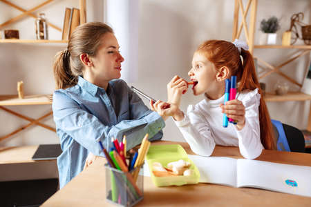 Portrait of happy family, maother and little daughter doing homework together. Eating snacksの写真素材