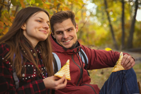 Cropped portrait of young beautiful couple having picnic at warm autumn day in the forest. Hiking...