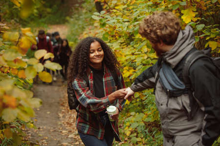 Cropped portrait of young beautiful couple spending time together with friends in the forest on warm...