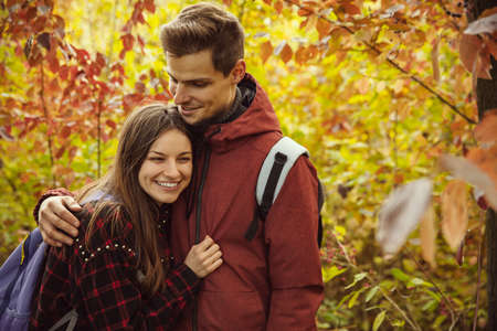 Cropped portrait of young beautiful couple spending time together in the forest on warm autumn day. Hiking activityの写真素材