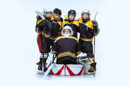 Full-length portrait of boys, children, professional hockeys player isolated over white background....