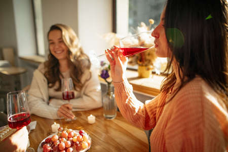 Cropped portrait of cheerful friends, woman and man, sitting at cafe and drinking wine. Celebrating successful dealの写真素材