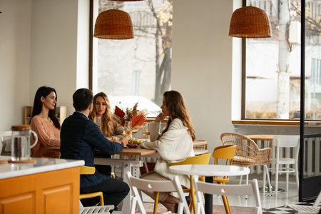 Cropped portrait of friends, man and three women celebrating event at cafe