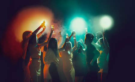 Group of young, active people at the night club, party dancing in neon lightsの写真素材