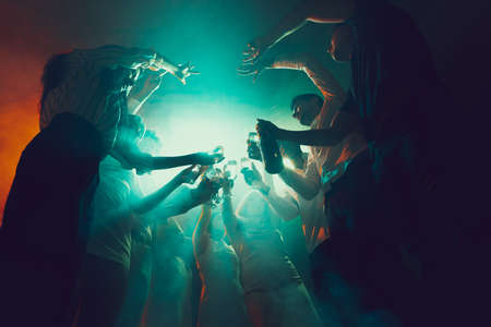 Group of young, active people at the night club, party dancing in neon lights, drinking cocktailsの写真素材