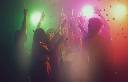 Group of young, active people at the night club, party dancing in neon lightsの写真素材