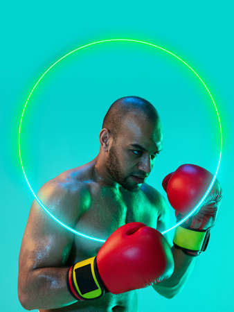Creative artwork of prfessional male boxer in motion over neon geometric element isolated over green backgroundの写真素材
